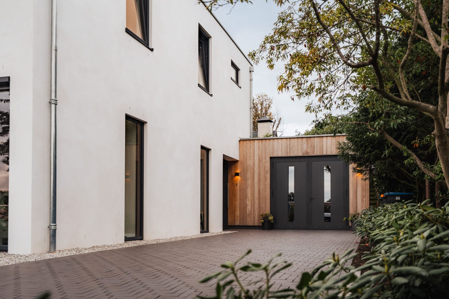 Oprit met houten garagedeuren langs de zijgevel van de villa