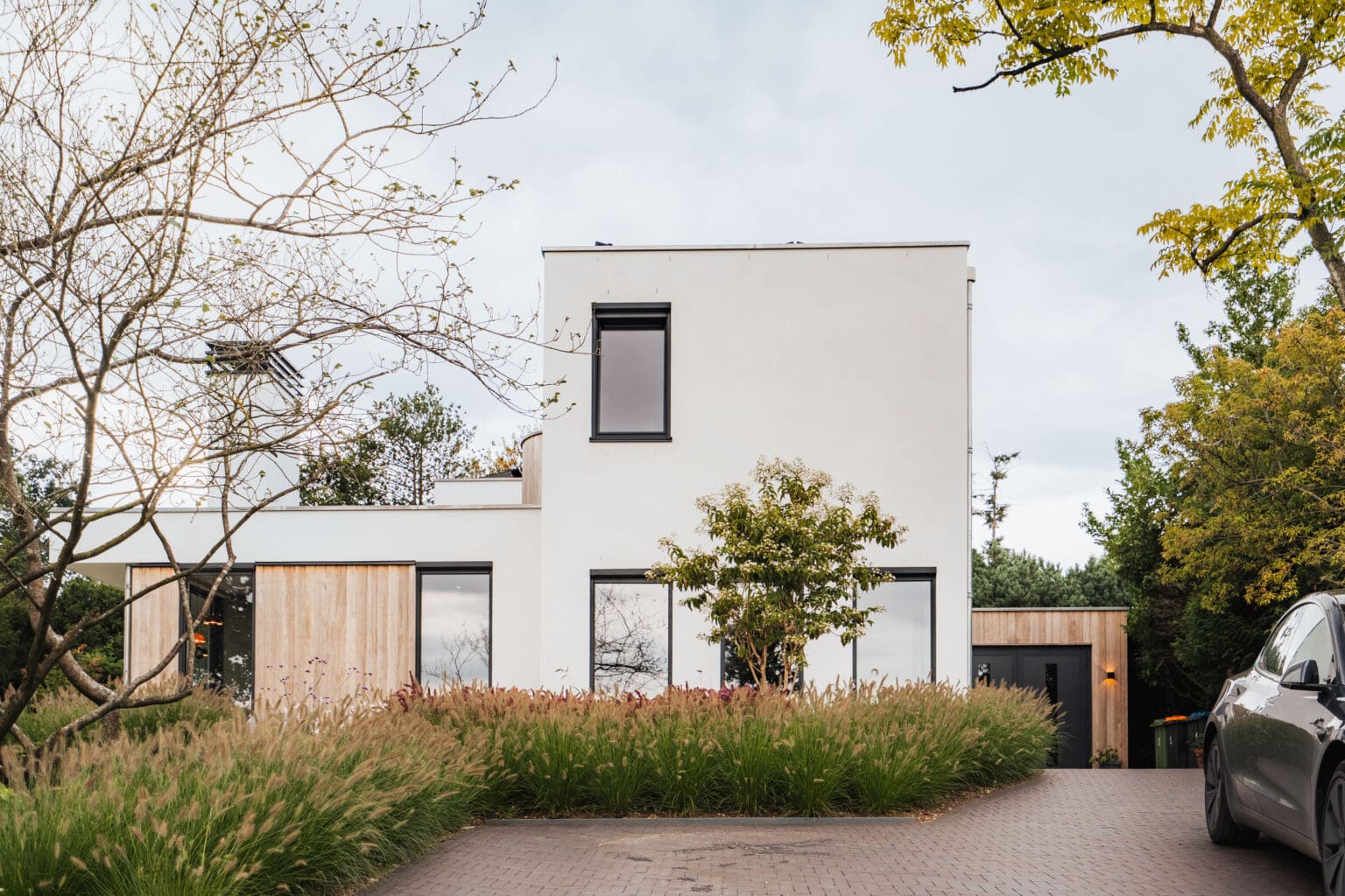 Voorgevel van de villa tussen de herfstkleuren van de omliggende bomen