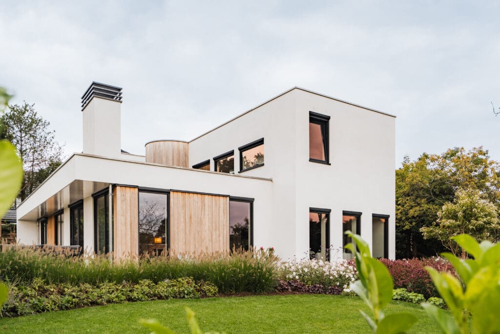 Vrijstaande villa in Leersum gezien vanaf het gazon, met witte stucgevels en houten gevelbekleding