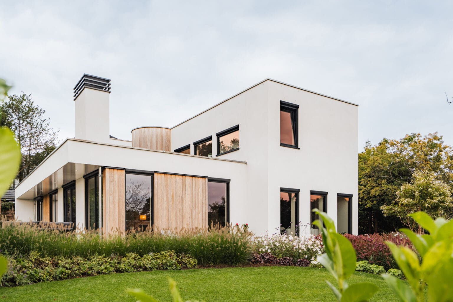 Vrijstaande villa in Leersum gezien vanaf het gazon, met witte stucgevels en houten gevelbekleding