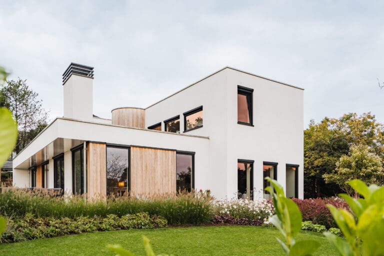 Vrijstaande villa in Leersum gezien vanaf het gazon, met witte stucgevels en houten gevelbekleding