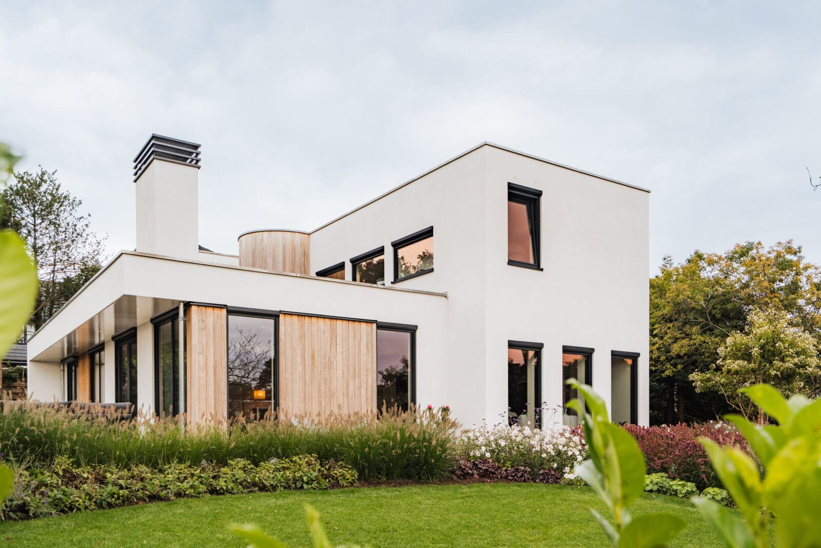 Vrijstaande villa in Leersum gezien vanaf het gazon, met witte stucgevels en houten gevelbekleding
