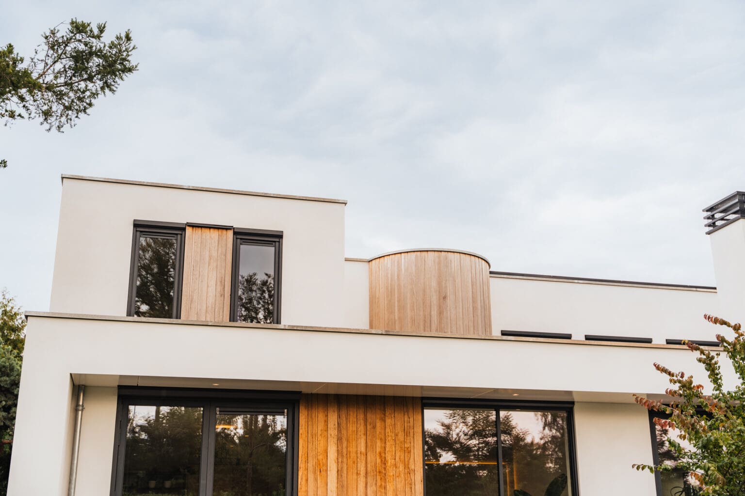Terugliggend bovenvolume van de villa met afgeronde houten hoek