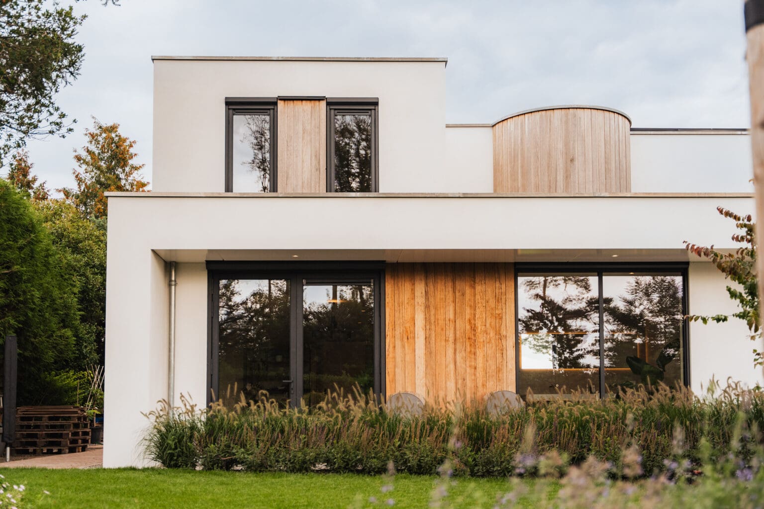 Tuingevel van de villa met hoge glaspuien en verticale houten gevelbekleding